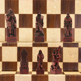A close-up of a handmade chess set with pieces designed in Celtic styles, set up on a wooden chess board.